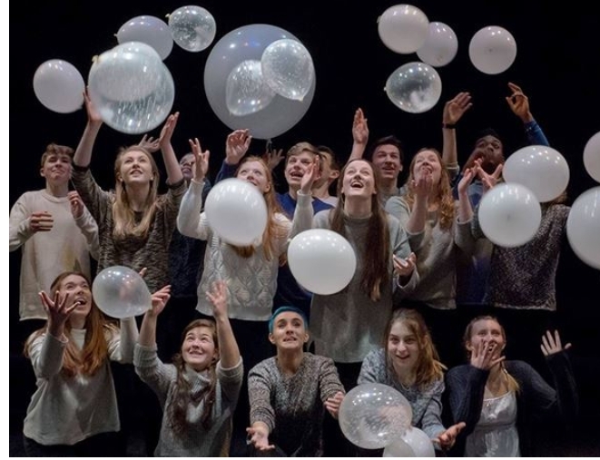 Lots Of Performers On Stage Catching White Balloons