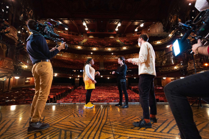 People being filmed and interviewed inside a theatre