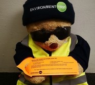 bear holding an orange bin tag