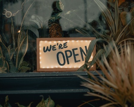 Open for business sign with plants