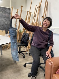 A lady holding some jeans that have been upcycled