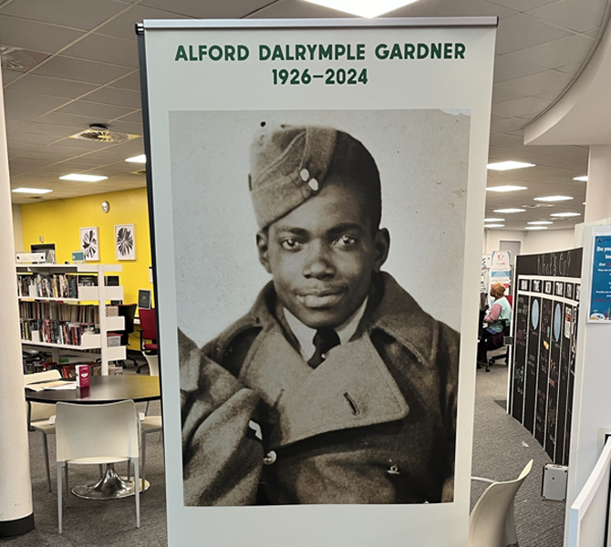Colour photograph showing a standing banner with the face of Alford Gardner