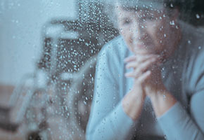 Sad older woman at rainy window