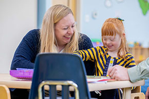 Child in classroom with adult smiling