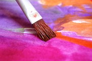 paintbrush on a canvas of pink, purple and blue paint