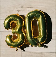 gold balloons of the number 30 on a wooden floor