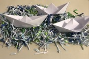 a photo of origami paper boats on a sea of blue tissue paper