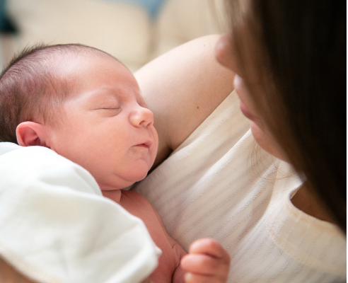 A newborn baby being cradled by its mum