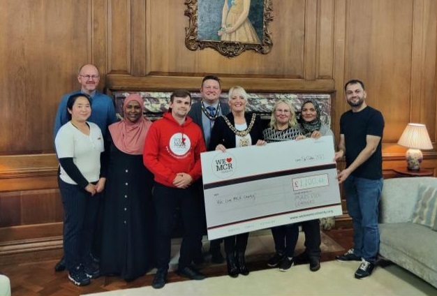 a group of learners holding and presenting a giant cheque to the Lord Mayor of Manchester. 