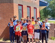 Group of children outside library building holding up books
