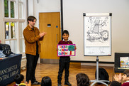 Boy holding picture, man clapping, flipchart board with illustration