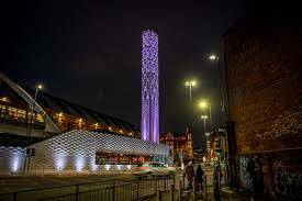 Manchester’s Tower of Light bathed in purple light. It is a 40 metre tall cylindrical structure