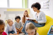 photo of an adult female reading to three young children