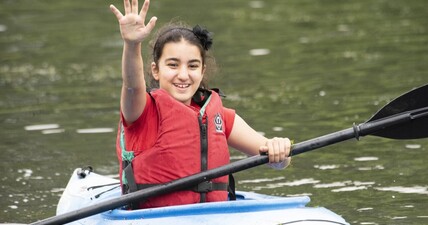 Girl waving from kayak