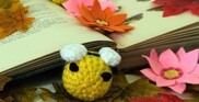 Photograph of handcrafted  crocheted bee and felt flowers nestling among books.