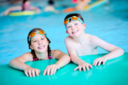 Two children smiling in a swimming pool