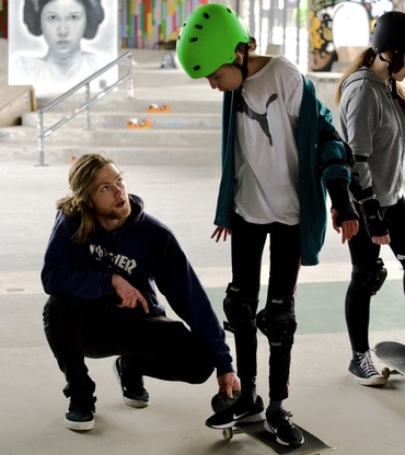 Young person being taught skateboarding