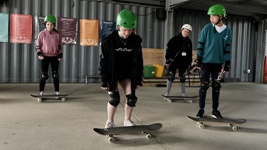 Young people learning skateboarding skills