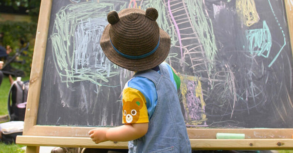 Young child drawing on a chalk board