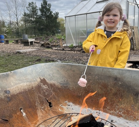 Girl holding marshmallow over an open fire