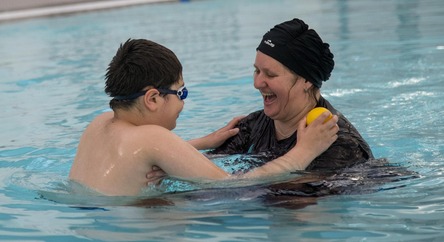 Mother helping her son swim