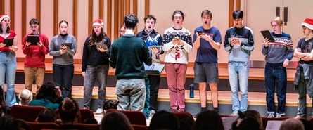 People singing in a row, wearing festive hats