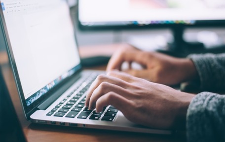 Hands typing on a laptop