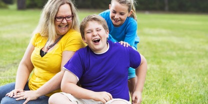 Young person sitting on grass with parents