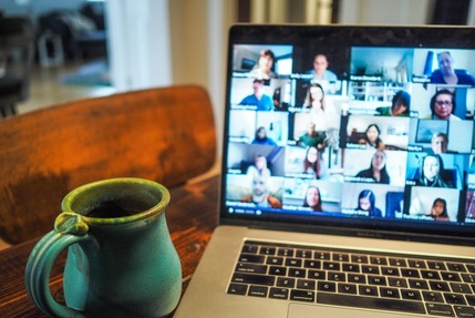 Computer with an online meeting and a coffee by it