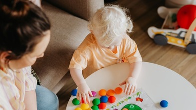 Young child playing, supervised by adult