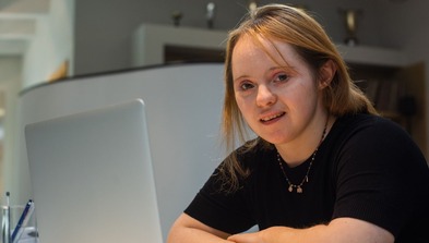 Learn disabled young woman sitting at computer smiling