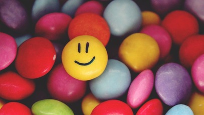 Smiling yellow smartie amongst other coloured smarties