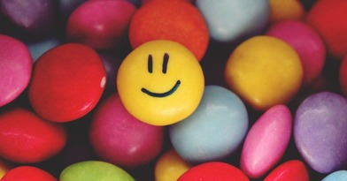 A smartie with a smiley face amongst plain smarties