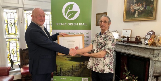 Mayor shaking hands with trail creator with logo in the background