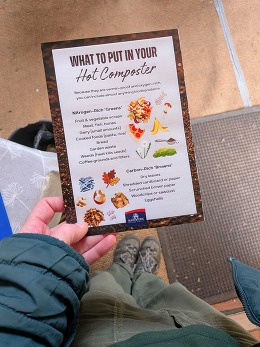 Someone holding a hot composting guide with feet on floor in the background