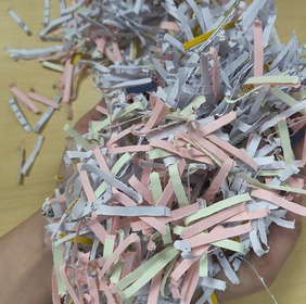Shredded paper in a mix of colours being held by a hand in a ball