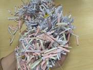 Shredded paper in a mix of colours being held by a hand in a ball