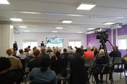 people watching speaker with presentation screen