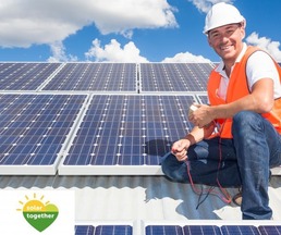 installer on a roof next to solar panels
