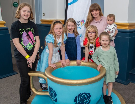 Children and young people with a prop teacup at our Alice in Wonderland Afternoon Tea.