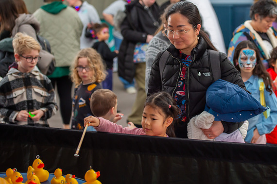 Family having a go at 'Hook-A-Duck' at our Family Fun Fair, celebrating Diversity, Inclusion, and Culture. 