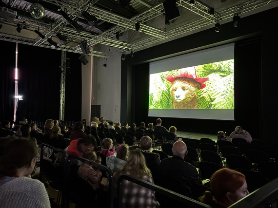 Children, young people, and families seated to watch Paddington In Peru
