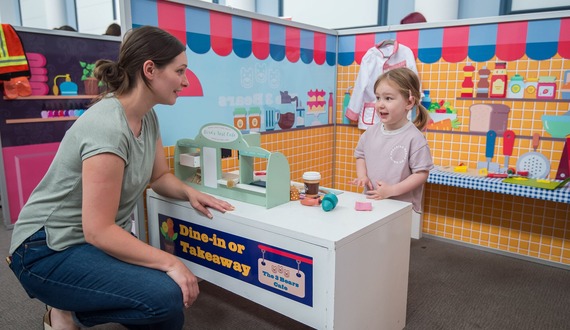 A child roleplaying with their parent/carer as a restaurant owner.