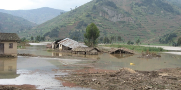 A rural mountain village that has suffered from flooding, with collapsed homes submerged in flood water.