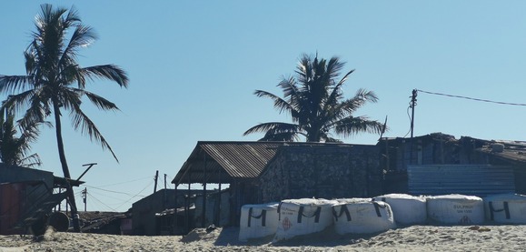 A southern African town with stone buildings and trees on the sand