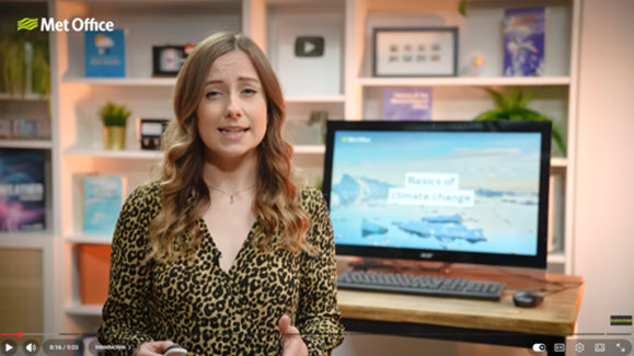 Honor Criswick in a Met Office studio explains climate change, with a screen showing melting ice and the words “Basics of climate change”.
