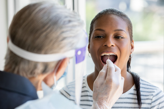 Woman opens mouth for cheek and throat swab while being tested for Covid-19 coronavirus stock photo