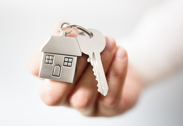 A hand holding a set of keys with a house-shaped keyring 