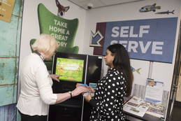 staff showing customer how to use self service machine