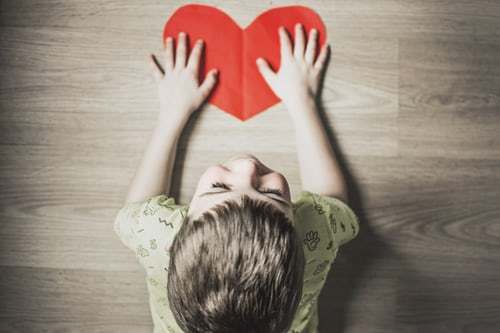 child playing on floor with heart shape 